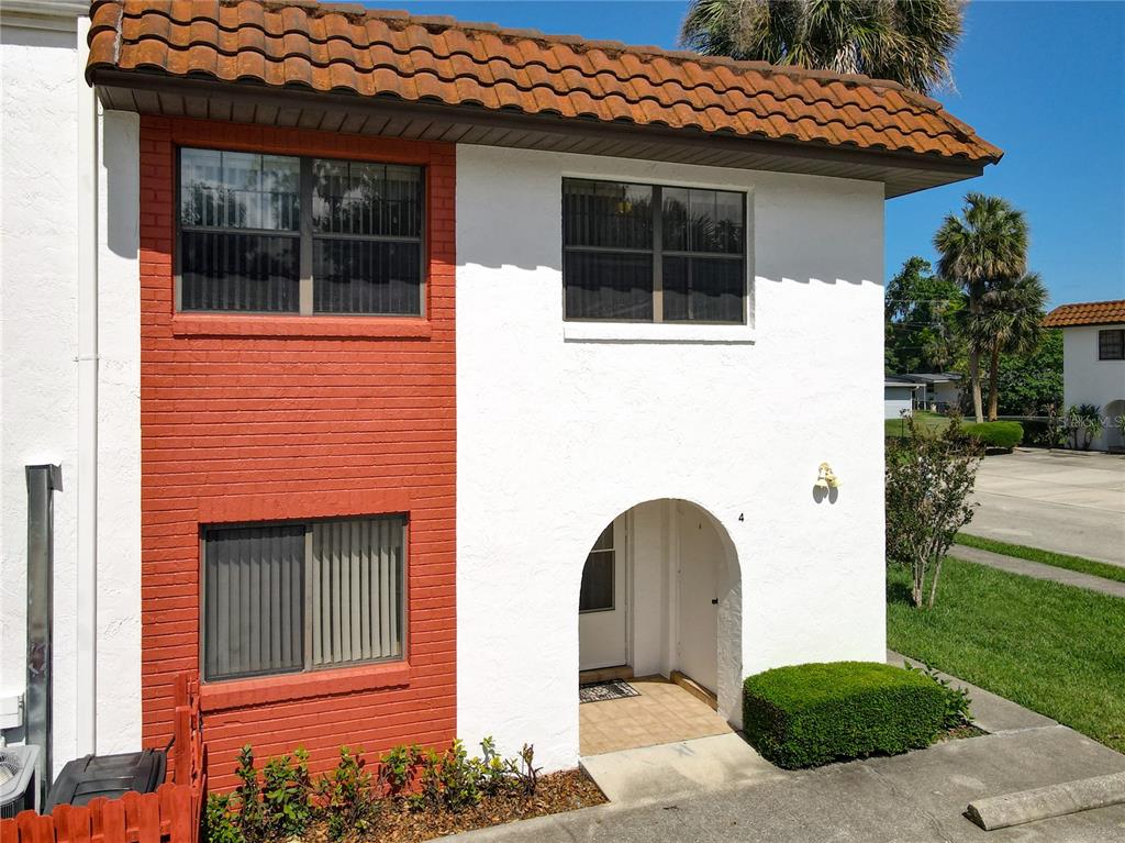 A two-story townhouse exterior features white stucco walls, red brick accents, and a tiled roof — 910 BIG TREE ROAD UNIT 12-4, SOUTH DAYTONA, FL