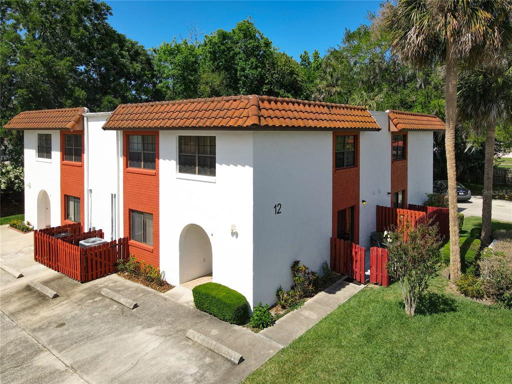An exterior view of a two-story apartment building with white walls and red accents — 910 BIG TREE ROAD UNIT 12-4, SOUTH DAYTONA, FL