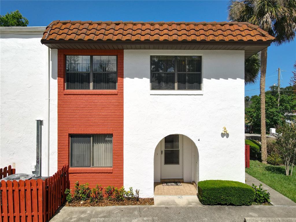 A two-story townhouse exterior features white stucco walls, red brick accents, and a tiled roof — 910 BIG TREE ROAD UNIT 12-4, SOUTH DAYTONA, FL