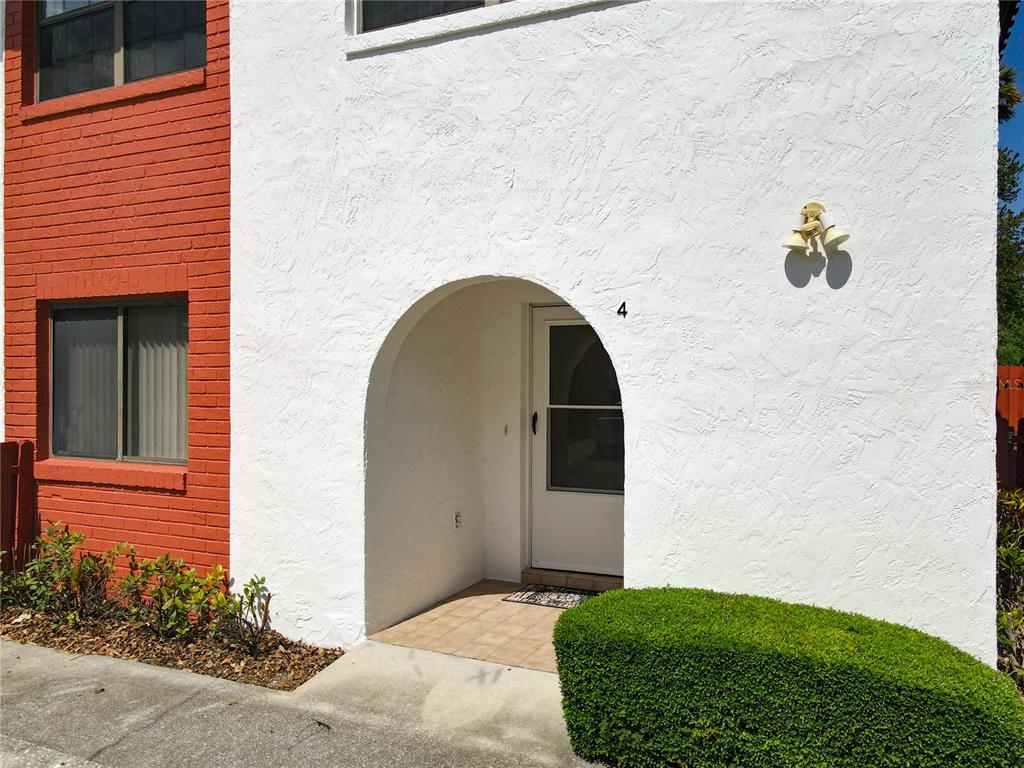 The exterior of a white stucco building features an arched entryway and a brick section — 910 BIG TREE ROAD UNIT 12-4, SOUTH DAYTONA, FL