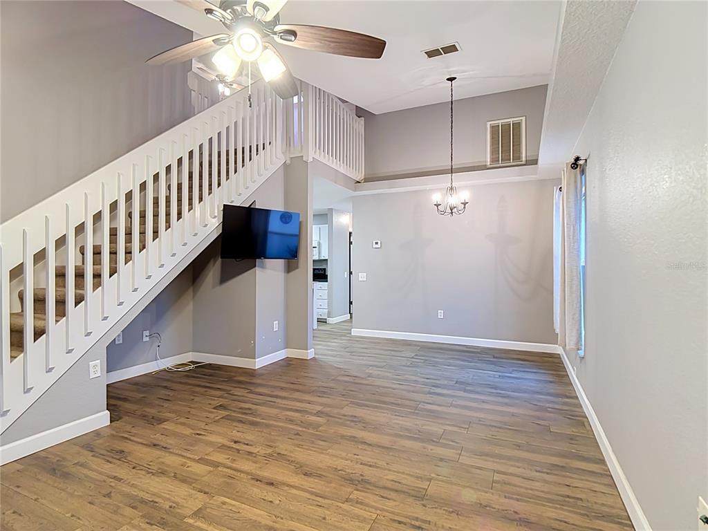 A living and dining area features wood-look flooring, a staircase, and a vaulted ceiling — 1436 SHIRLEY DRIVE, LAKELAND, FL