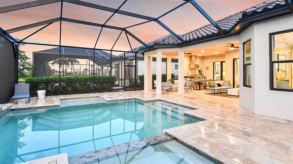 A screened-in patio features a swimming pool, a hot tub, and an outdoor living area — 7712 MOONBEAM AVENUE, SARASOTA, FL