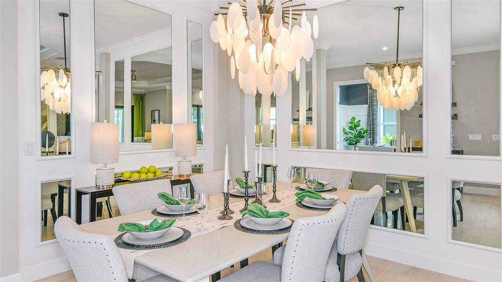 A dining room features a large chandelier, mirrored wall panels, and a table set for six — 7712 MOONBEAM AVENUE, SARASOTA, FL