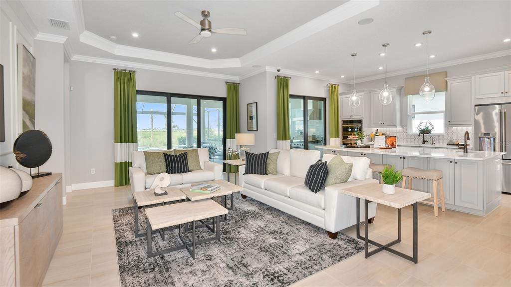 An open-concept living room and kitchen feature light cabinetry, a large island, and sliding doors — 7712 MOONBEAM AVENUE, SARASOTA, FL