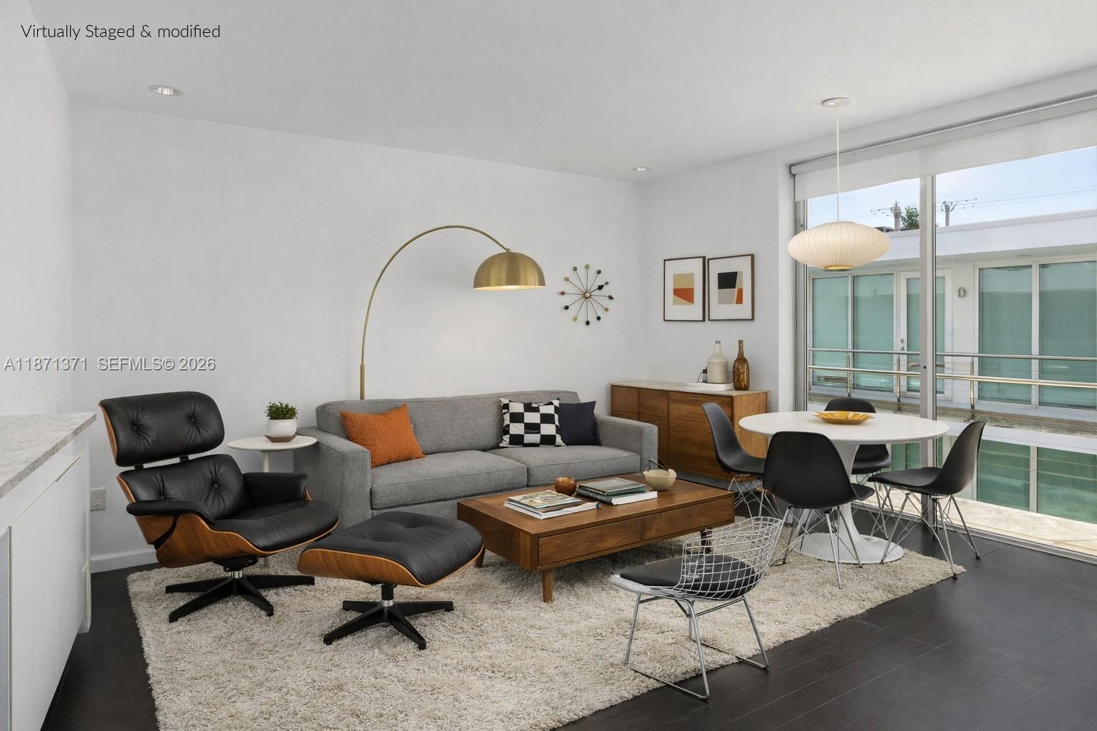 This virtually staged living and dining area features mid-century modern furniture on a dark floor — 1601 West Ave # 210, Miami Beach FL 33139, MIAMI BEACH, FL