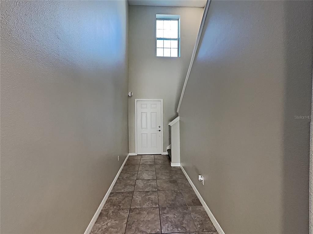 A tiled entryway features a high ceiling, a white door, and a staircase — 15320 BROAD BRUSH DRIVE, RUSKIN, FL