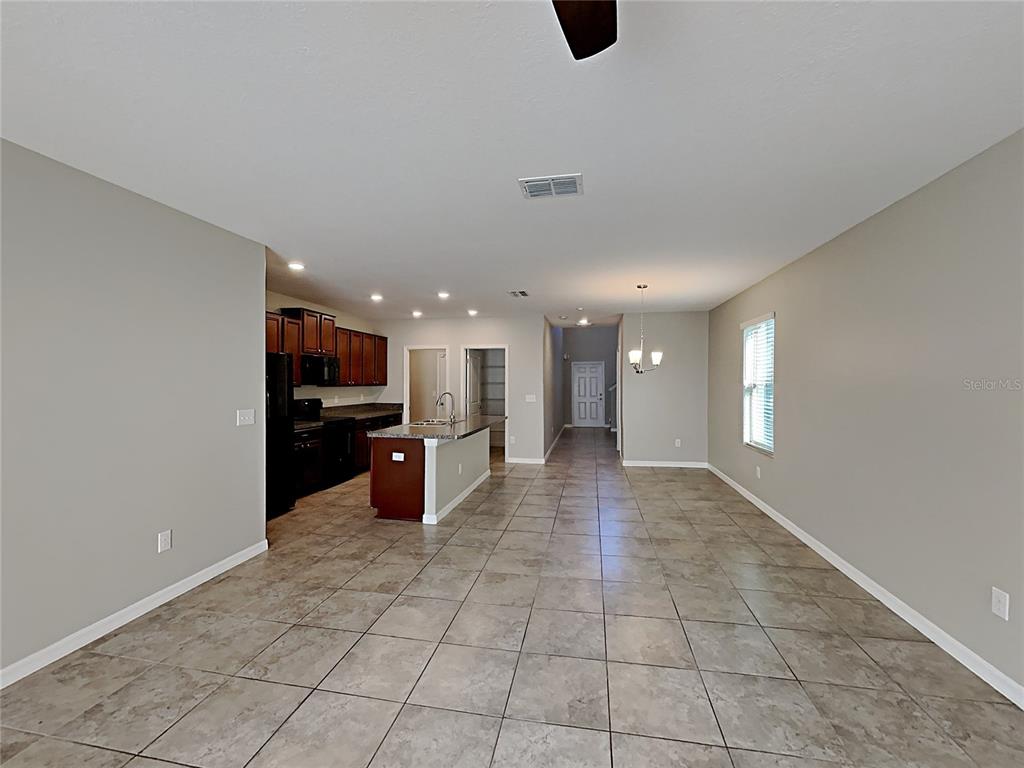 An open-concept kitchen and dining area features dark wood cabinets, an island, and tile flooring — 15320 BROAD BRUSH DRIVE, RUSKIN, FL