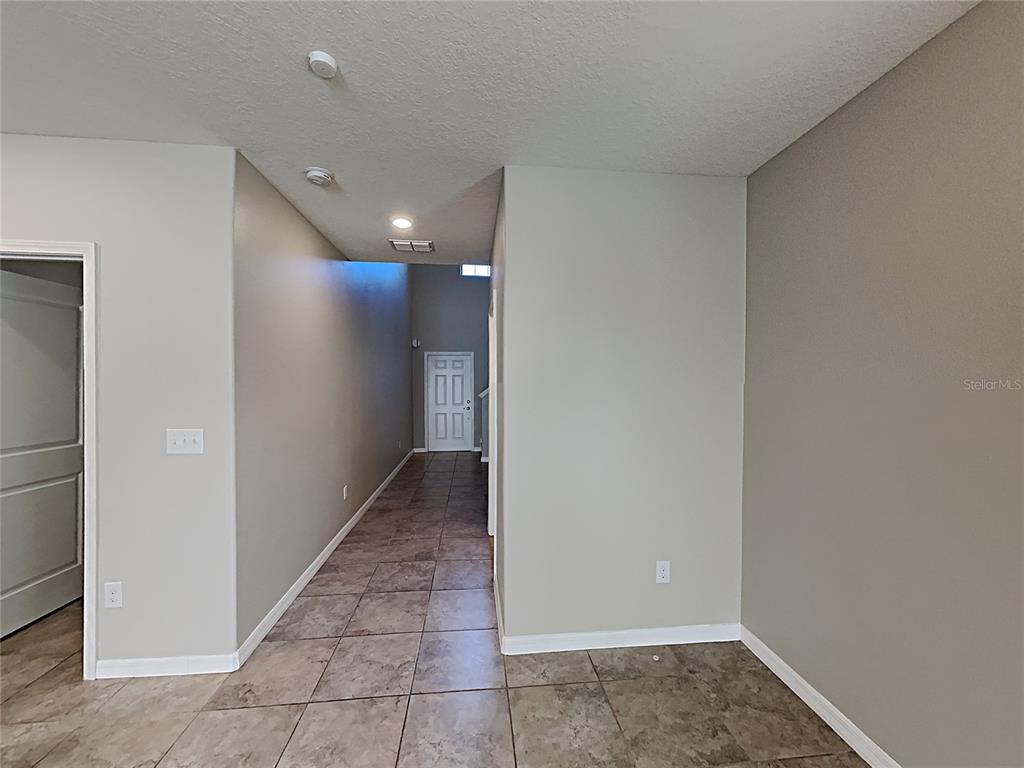 A tiled hallway leads toward a white door in a room with neutral walls — 15320 BROAD BRUSH DRIVE, RUSKIN, FL