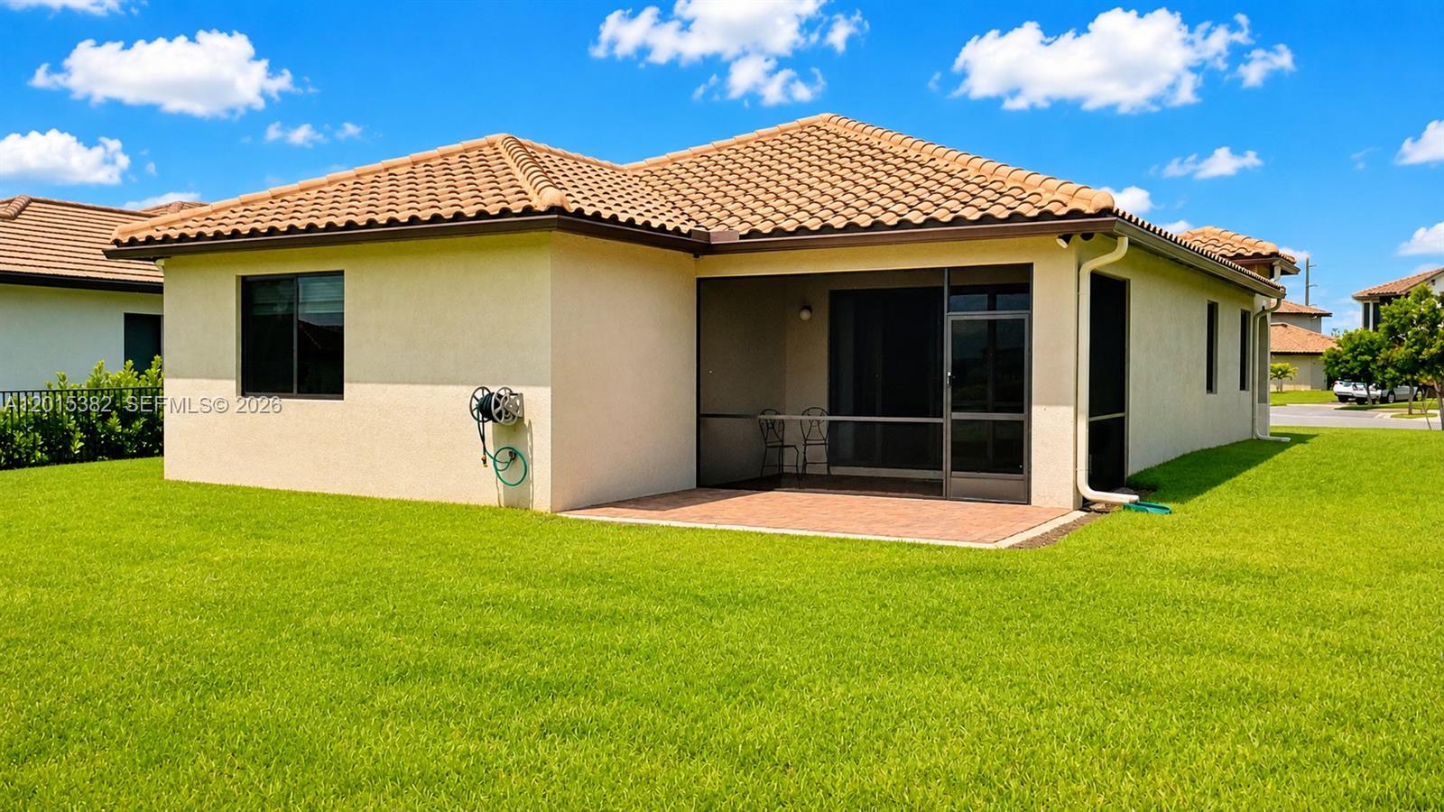 The exterior of a house features a tiled roof, a screened-in patio, and a lawn — 4989 OFANTO LN, Ave Maria FL 34142, AVE MARIA, FL
