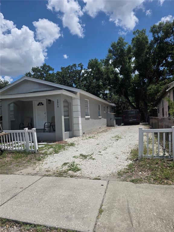 A single-story house with a white porch, gravel driveway, and a white picket fence — 2619 E CHELSEA STREET, TAMPA, FL