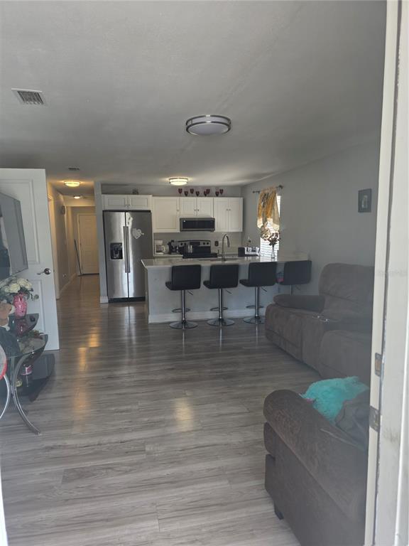 An open-concept kitchen and living area features light wood flooring and a breakfast bar — 2619 E CHELSEA STREET, TAMPA, FL