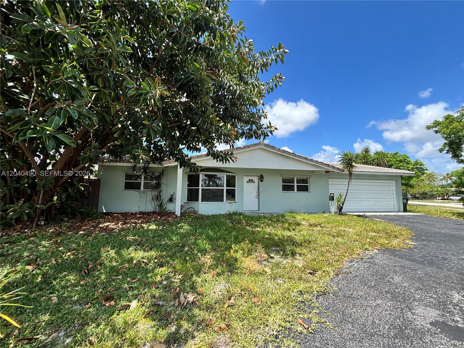 A single-story house with a light green exterior, a garage, and a large tree — 4300 NW 9th Ct, Coconut Creek FL 33066, COCONUT CREEK, FL