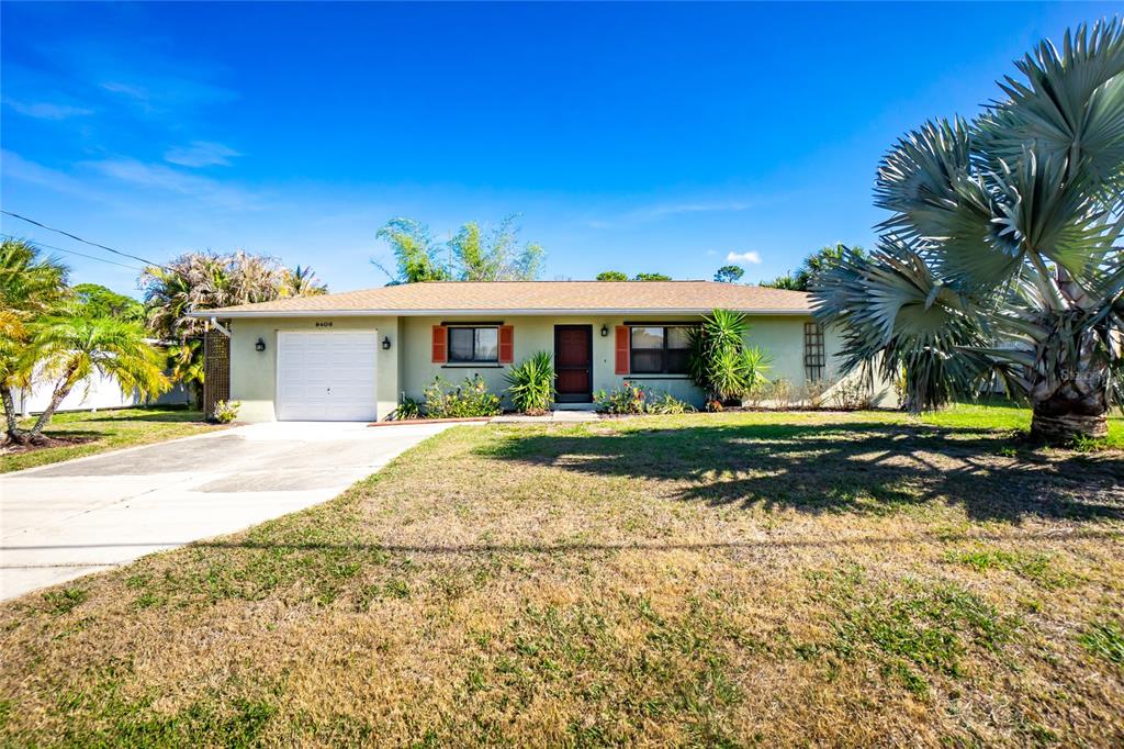 A single-story house with a garage, light green siding, and a palm tree in front — 9406 PROSPECT AVENUE, ENGLEWOOD, FL