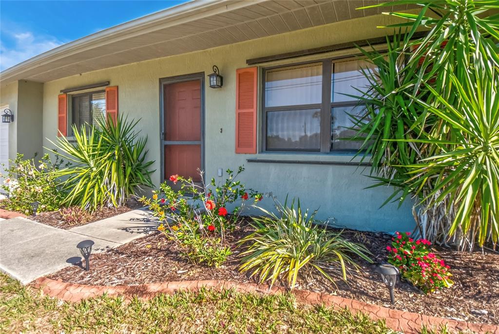 The exterior of a single-story house features a front door, windows with shutters, and landscaping — 9406 PROSPECT AVENUE, ENGLEWOOD, FL