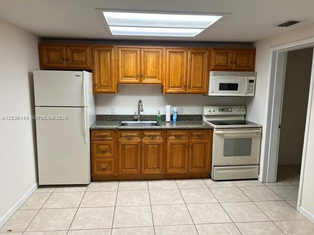 A kitchen features wooden cabinets, a white refrigerator, a white stove, and tiled flooring — TAMARAC, FL