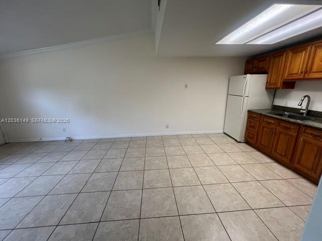 This kitchen features light-colored tile flooring, wooden cabinets, and a white refrigerator — TAMARAC, FL