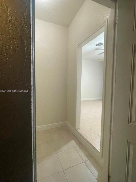A narrow hallway with light-colored tile flooring leads to an open doorway into another room — MIAMI, FL