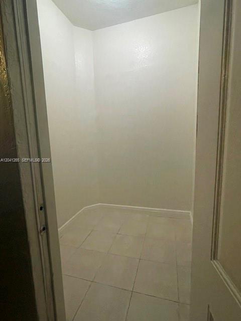 A small, empty closet with white walls and light-colored tile flooring — MIAMI, FL