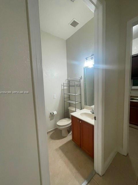 A small bathroom features a wood vanity, a toilet, and a metal storage rack — MIAMI, FL