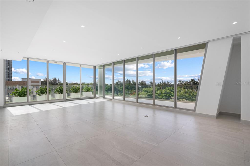 An empty room with large floor-to-ceiling windows, light tile flooring, and a balcony view — 540 DE LA CONSTITUCION AVENUE UNIT 701, SAN JUAN, PR