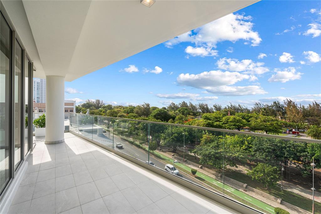 A tiled balcony with a glass railing overlooks a park, a road, and a blue sky — 540 DE LA CONSTITUCION AVENUE UNIT 701, SAN JUAN, PR