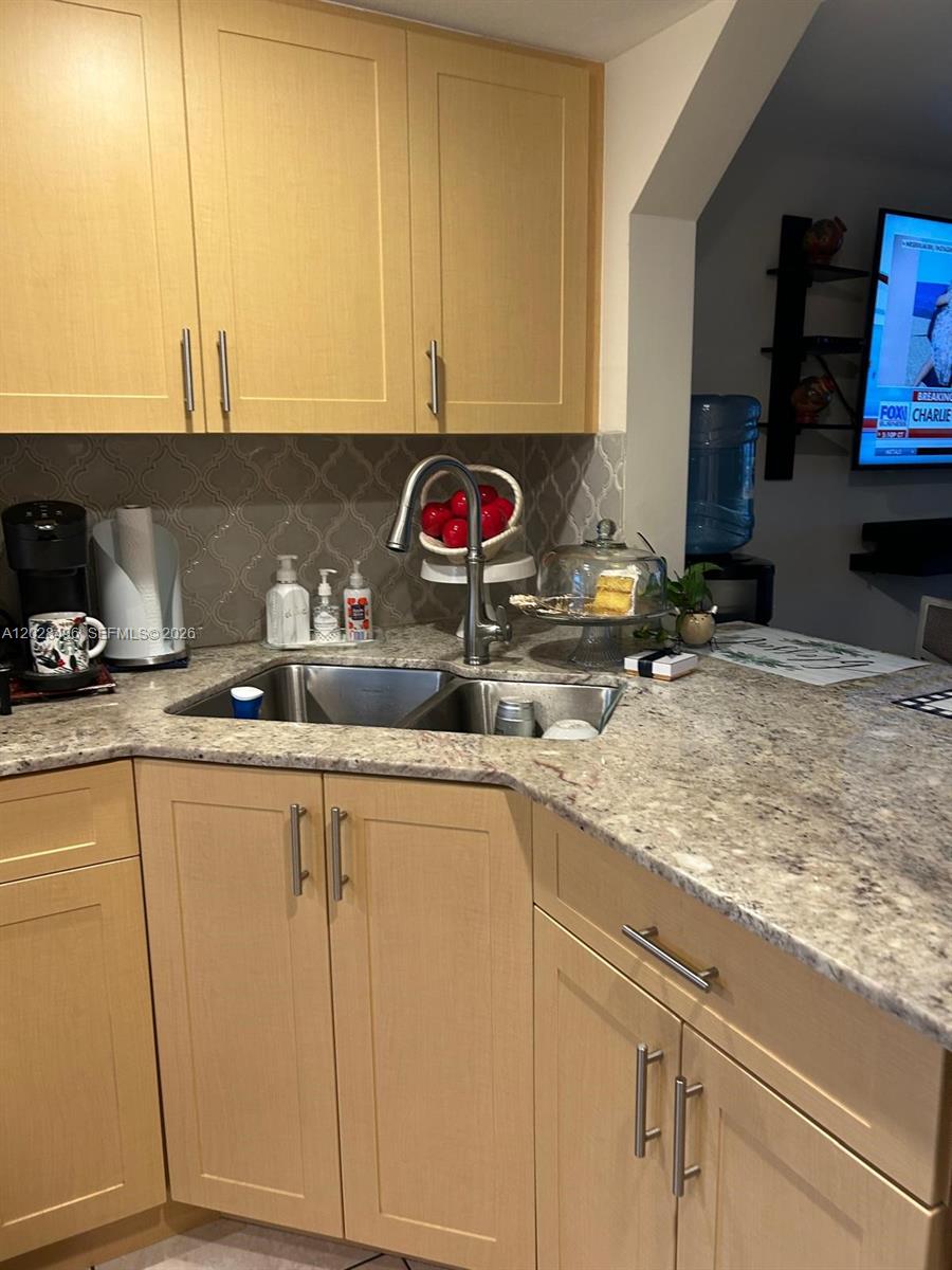 A kitchen features light wood cabinets, granite countertops, a stainless steel stove, and patterned backsplash — 7033 NW 169th St, Hialeah FL 33015, HIALEAH, FL