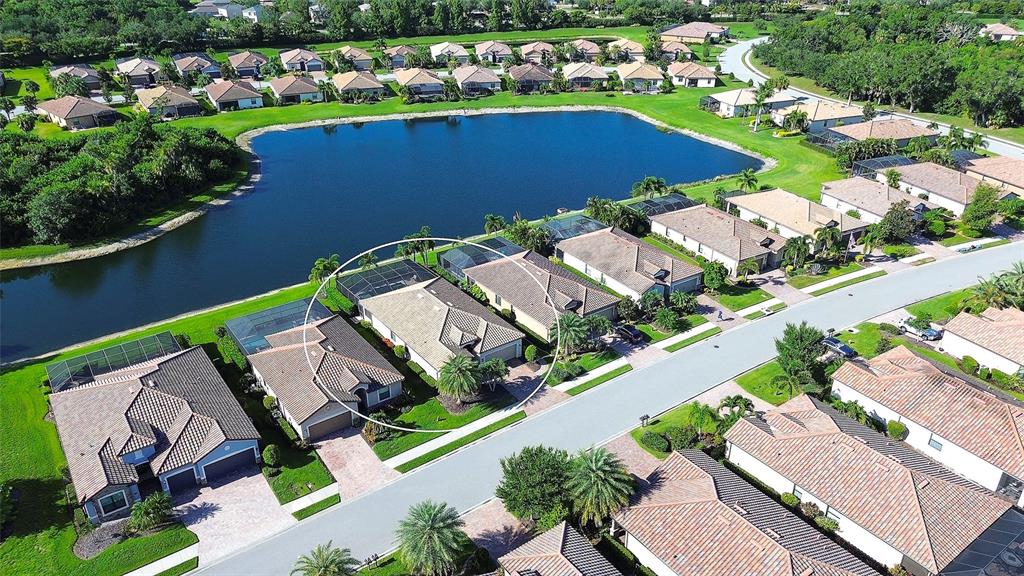 An aerial view shows a suburban neighborhood with a lake and a circled house — 7130 QUIET CREEK DRIVE, BRADENTON, FL