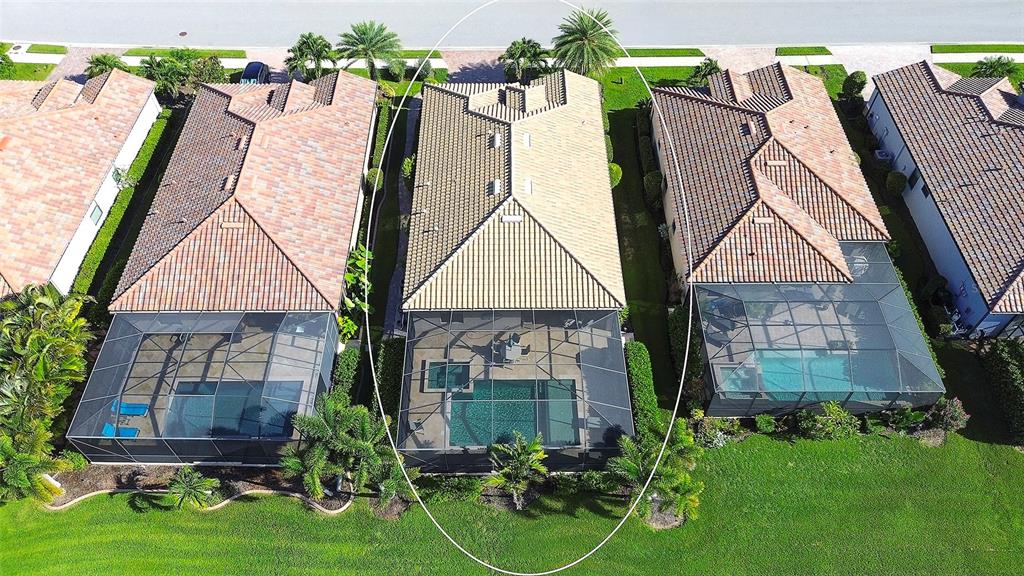 An aerial view shows a house with a tiled roof and a screened-in pool enclosure — 7130 QUIET CREEK DRIVE, BRADENTON, FL