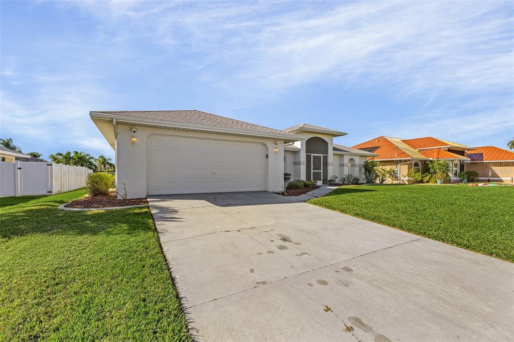 A single-story house with a white garage, concrete driveway, and a green lawn — 1230 SW 4TH AVENUE, CAPE CORAL, FL