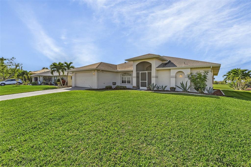 A single-story house with a beige exterior, a two-car garage, and a large front lawn — 1230 SW 4TH AVENUE, CAPE CORAL, FL