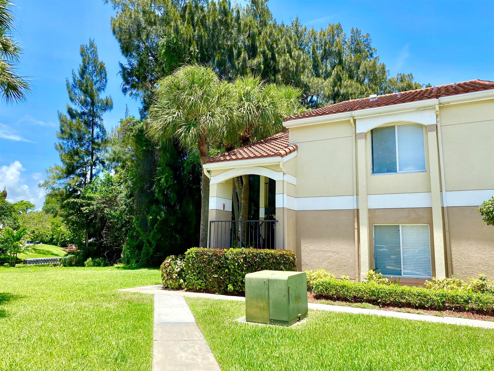 A two-story apartment building exterior with a concrete walkway, green lawn, and palm trees — 815 W Boynton Beach Boulevard # 201, Boynton Beach FL 33426, BOYNTON BEACH, FL