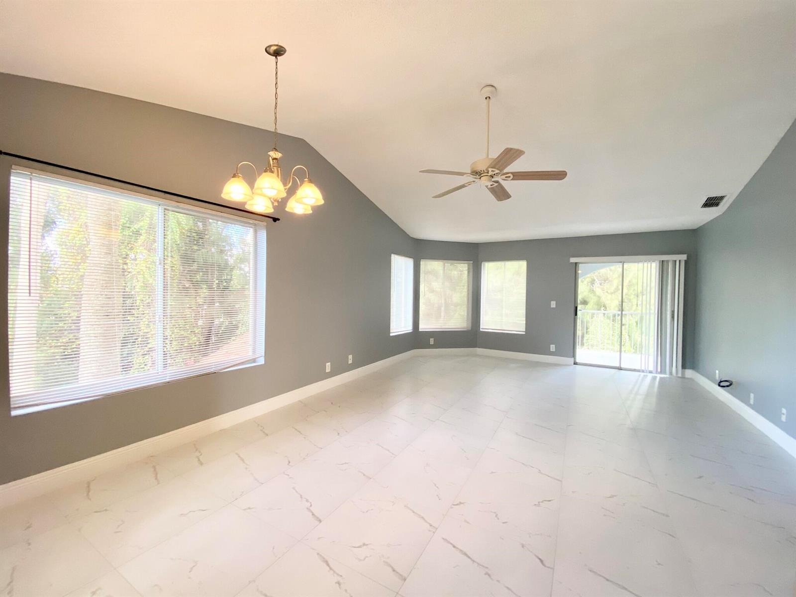 A bright, empty room features gray walls, white marble-look tile flooring, and a vaulted ceiling — 815 W Boynton Beach Boulevard # 201, Boynton Beach FL 33426, BOYNTON BEACH, FL