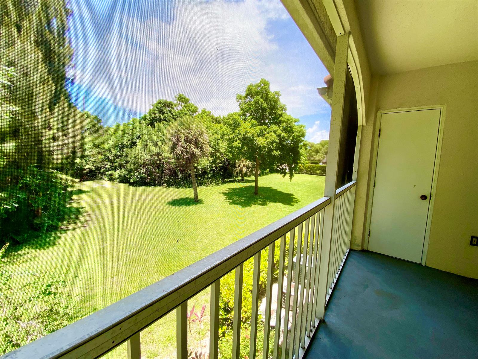 A screened-in balcony overlooks a grassy yard with trees and a white storage closet door — 815 W Boynton Beach Boulevard # 201, Boynton Beach FL 33426, BOYNTON BEACH, FL