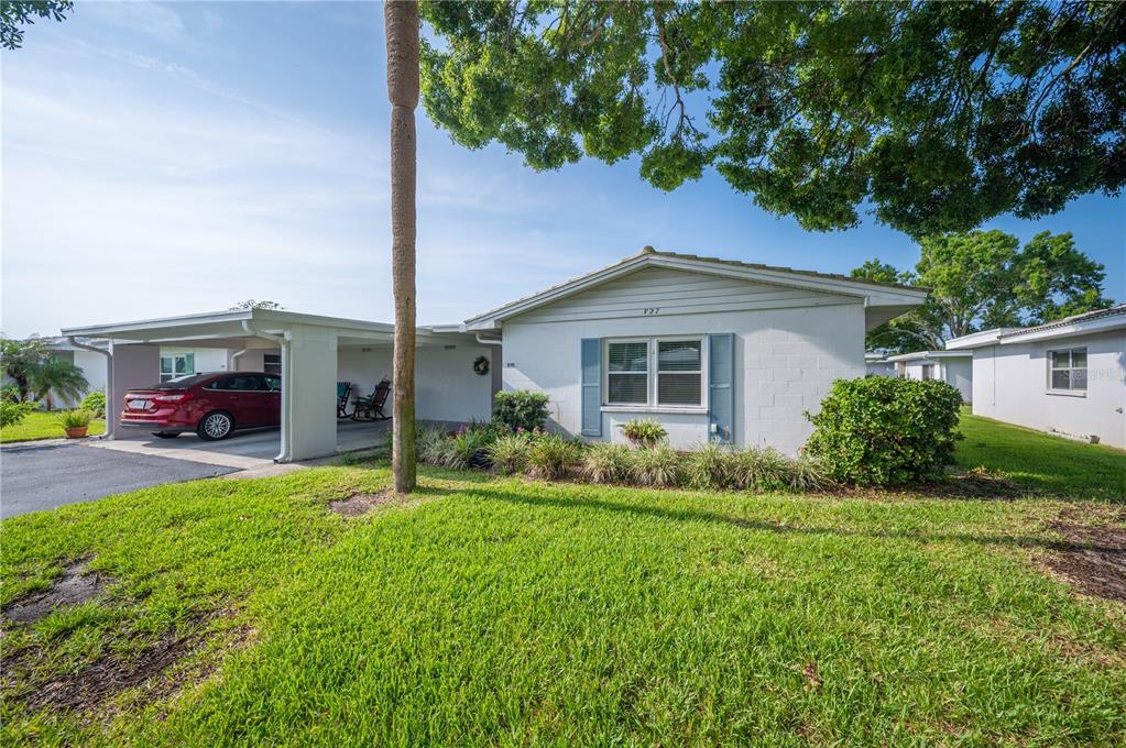A white single-story house with a carport and a red car parked in the driveway — 616 COTTAGE LANE UNIT 616, LAKELAND, FL