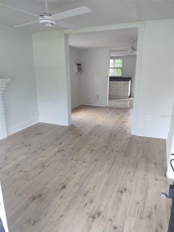 An interior view shows a living room with light wood flooring leading into a kitchen — 2120 CARLTON DRIVE, ORLANDO, FL