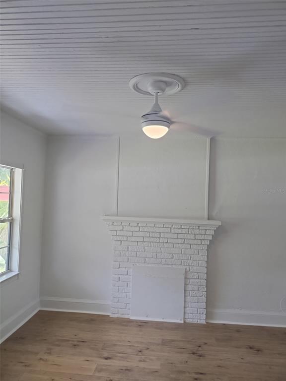 A room with light wood floors, white walls, a white brick fireplace, and a ceiling fan — 2120 CARLTON DRIVE, ORLANDO, FL