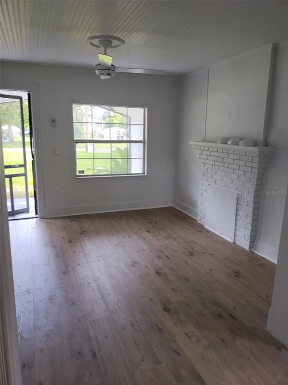 A living room features light wood flooring, a white brick fireplace, and a ceiling fan — 2120 CARLTON DRIVE, ORLANDO, FL