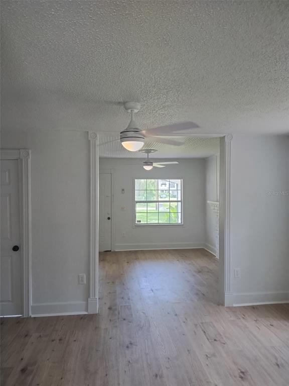 A room with light wood flooring and two ceiling fans leads to an adjacent sunlit space — 2120 CARLTON DRIVE, ORLANDO, FL