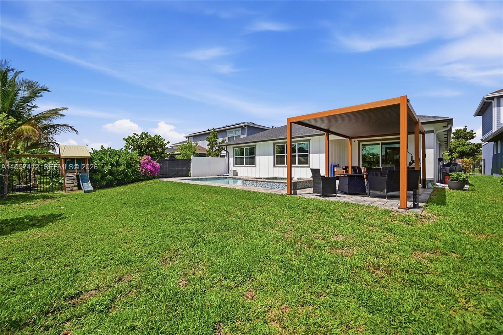 A backyard features a swimming pool, a wooden pergola, and a small children's play set — 1322 TIMBER REAP TRL, Loxahatchee FL 33470, LOXAHATCHEE, FL