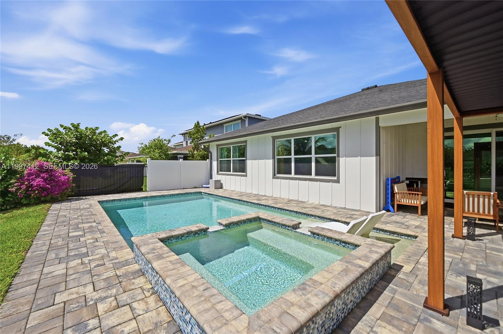A backyard features a swimming pool with an attached spa and a paved patio area — 1322 TIMBER REAP TRL, Loxahatchee FL 33470, LOXAHATCHEE, FL