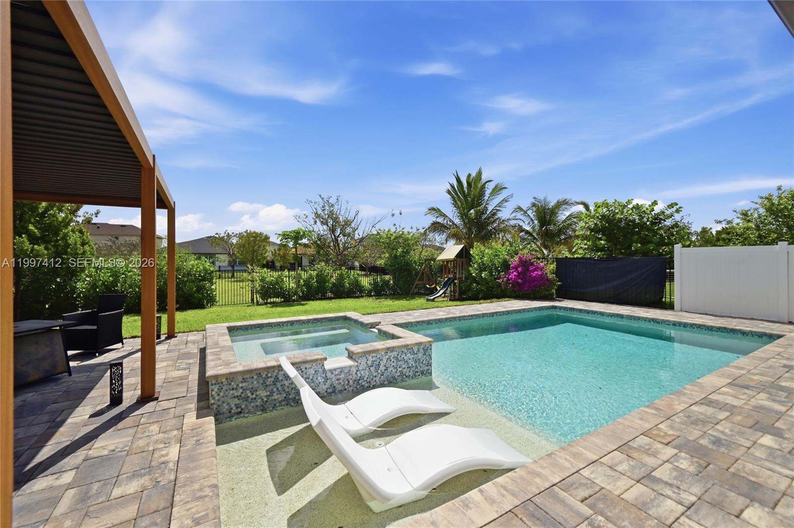 A backyard features a swimming pool with a tanning ledge, a spa, and patio furniture — 1322 TIMBER REAP TRL, Loxahatchee FL 33470, LOXAHATCHEE, FL