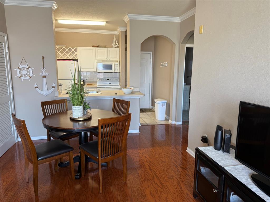 A dining area with a round wooden table sits adjacent to an open-concept kitchen — 1216 S MISSOURI AVENUE UNIT 406, CLEARWATER, FL