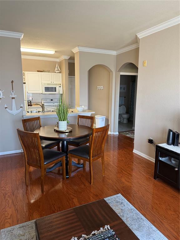 A dining area with a round wooden table sits adjacent to an open kitchen — 1216 S MISSOURI AVENUE UNIT 406, CLEARWATER, FL