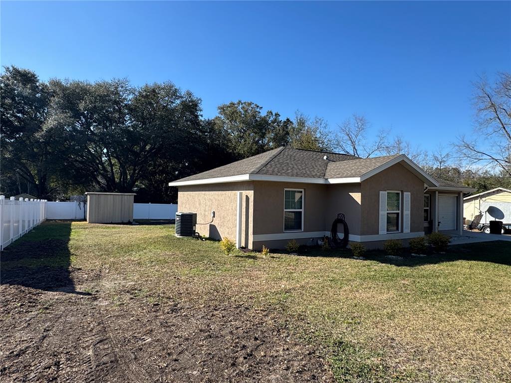 A tan stucco house with a gray shingled roof and a backyard shed — 14476 SE 34TH COURT, SUMMERFIELD, FL