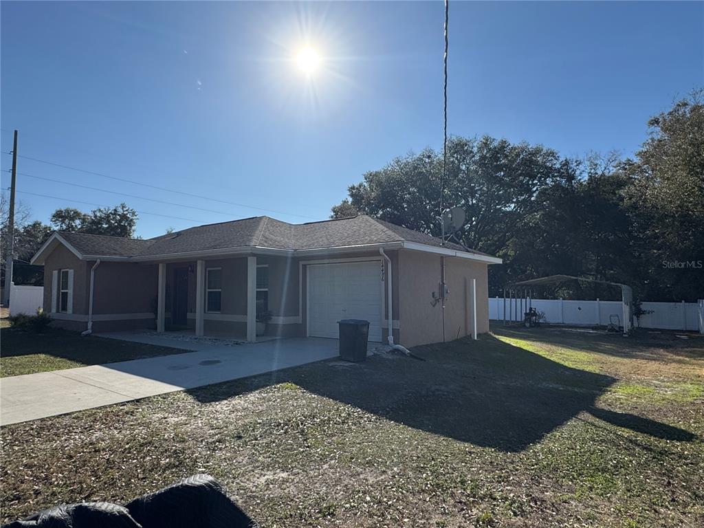 A single-story house with a tan stucco exterior, a garage, and a concrete driveway — 14476 SE 34TH COURT, SUMMERFIELD, FL