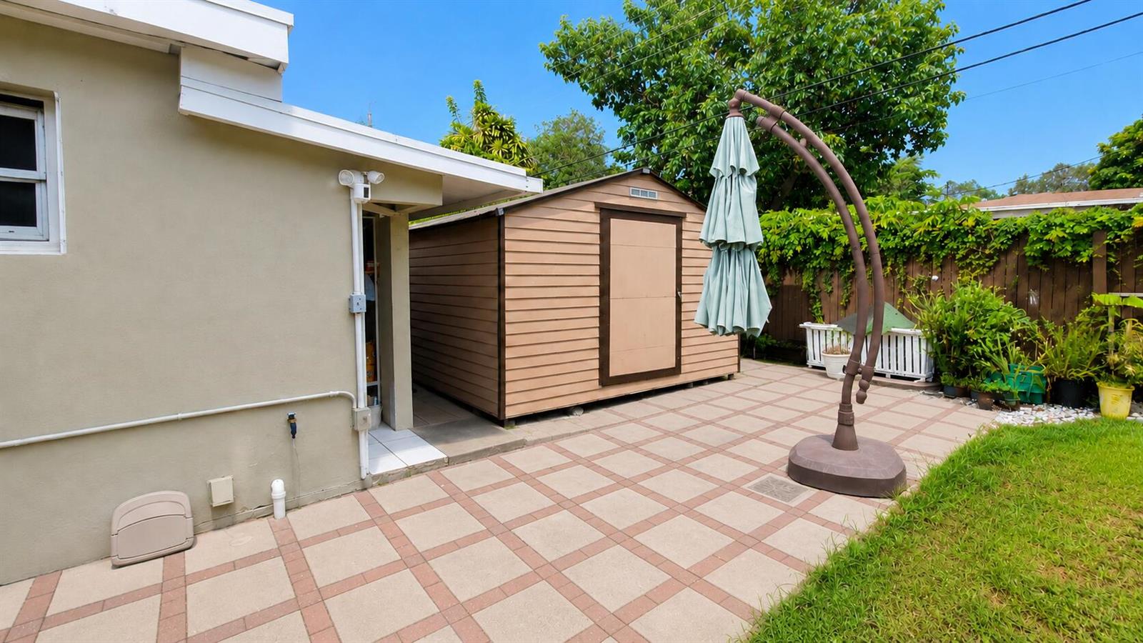 A beige house exterior features a patio, a storage shed, and a large patio umbrella — 2311 N 58th Avenue, Hollywood FL 33021, HOLLYWOOD, FL