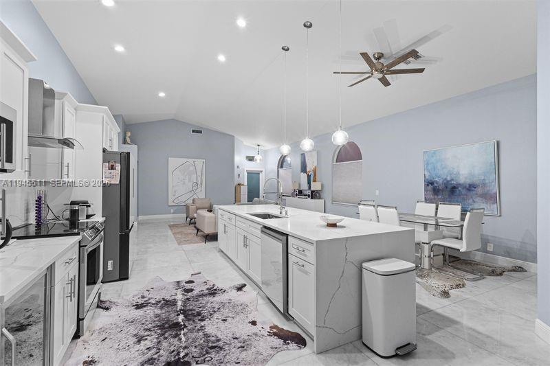 A modern kitchen features white cabinetry, a large marble-topped island, and light blue walls — 6952 NW 27th Ct # 6952, Margate FL 33063, MARGATE, FL