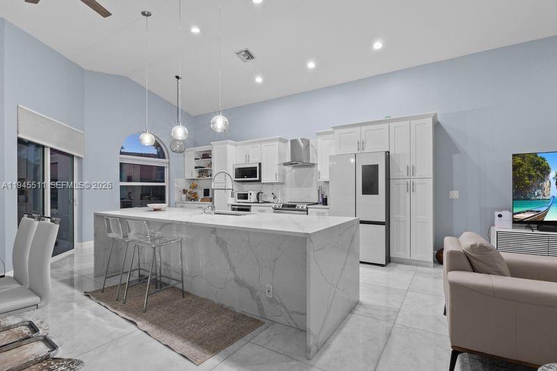 A modern kitchen features a large marble waterfall island, white cabinetry, and light tile flooring — 6952 NW 27th Ct # 6952, Margate FL 33063, MARGATE, FL