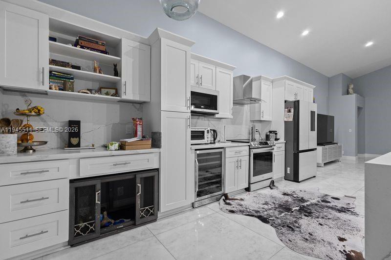A modern white kitchen features marble countertops, stainless steel appliances, and a built-in pet crate — 6952 NW 27th Ct # 6952, Margate FL 33063, MARGATE, FL