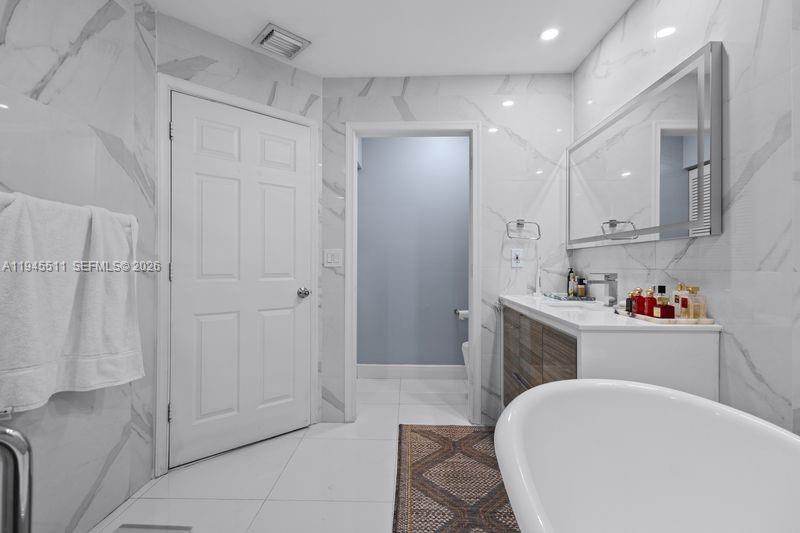 A bathroom features white marble-look wall tiles, a freestanding tub, and a modern vanity — 6952 NW 27th Ct # 6952, Margate FL 33063, MARGATE, FL
